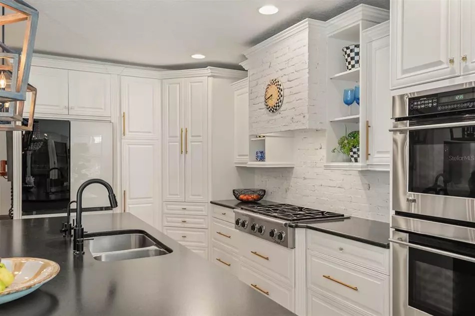 The chef's kitchen at 221 Minnehaha with travertine floors, honed black granite counters, a Dacor pro-grade gas cooktop, and a large island