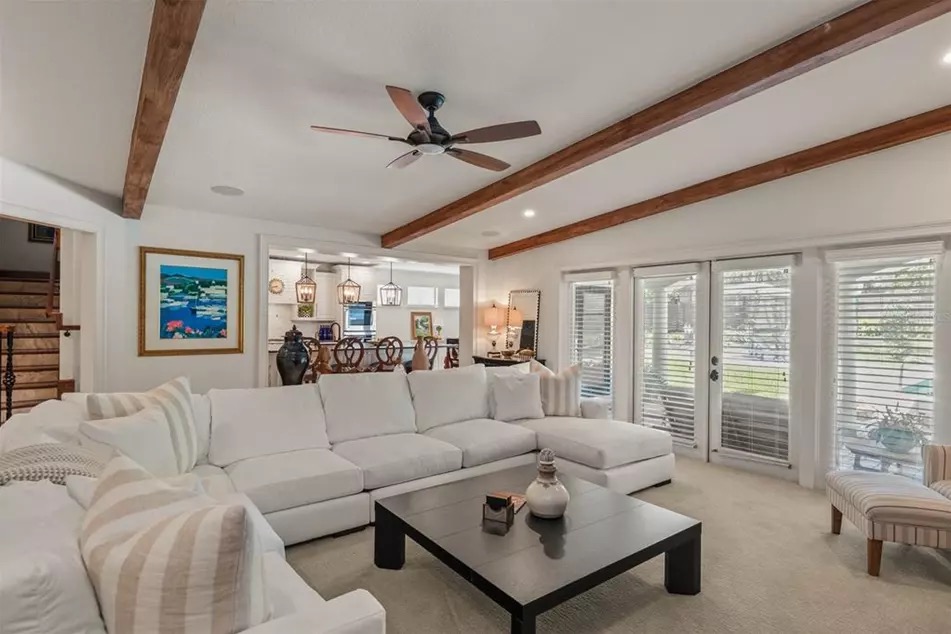The family room at 221 Minnehaha, with tall ceilings, decorative wood beams, and French doors opening to the back porch